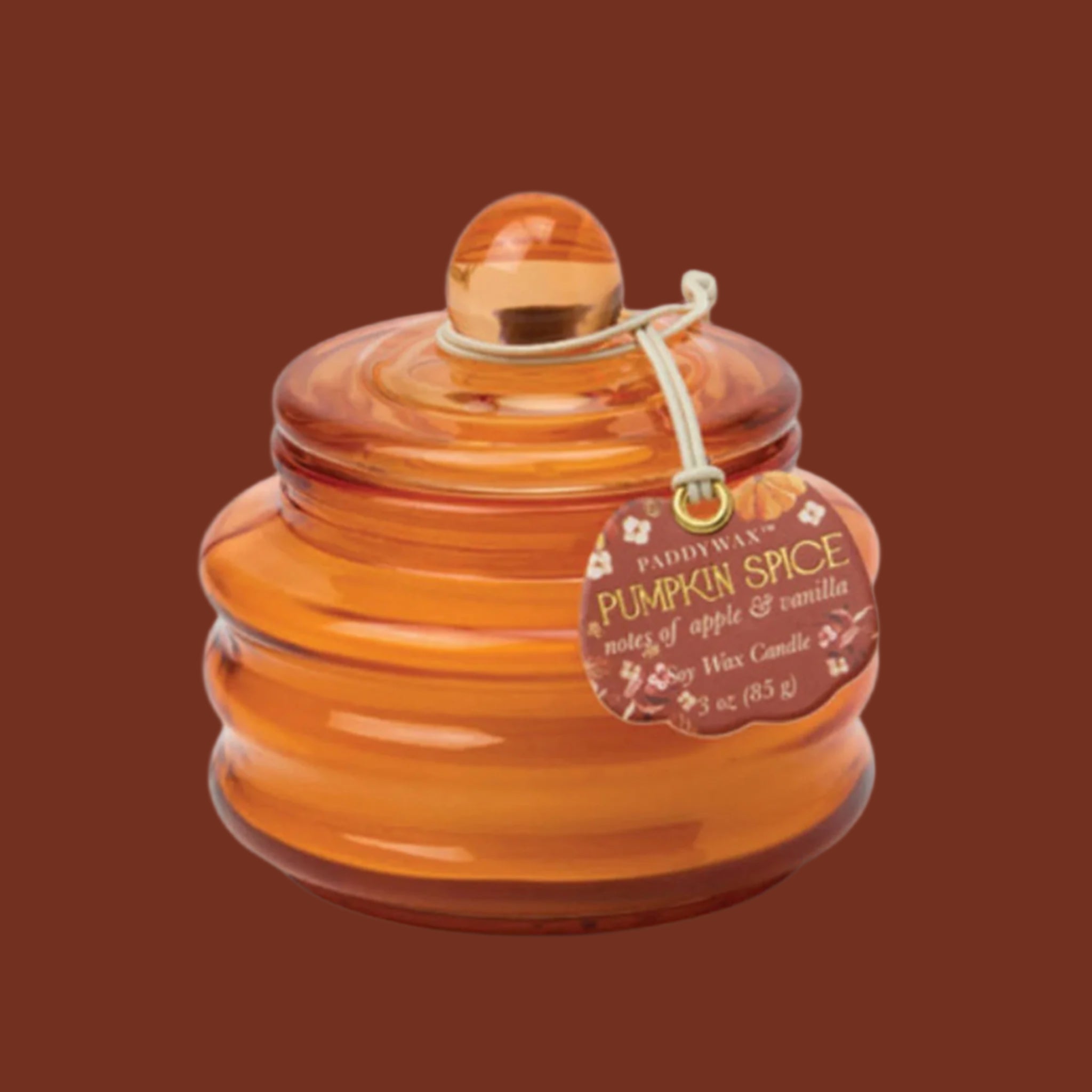 An orange glass candle with a label that reads, 'Paddywax Pumpkin Spice'. 