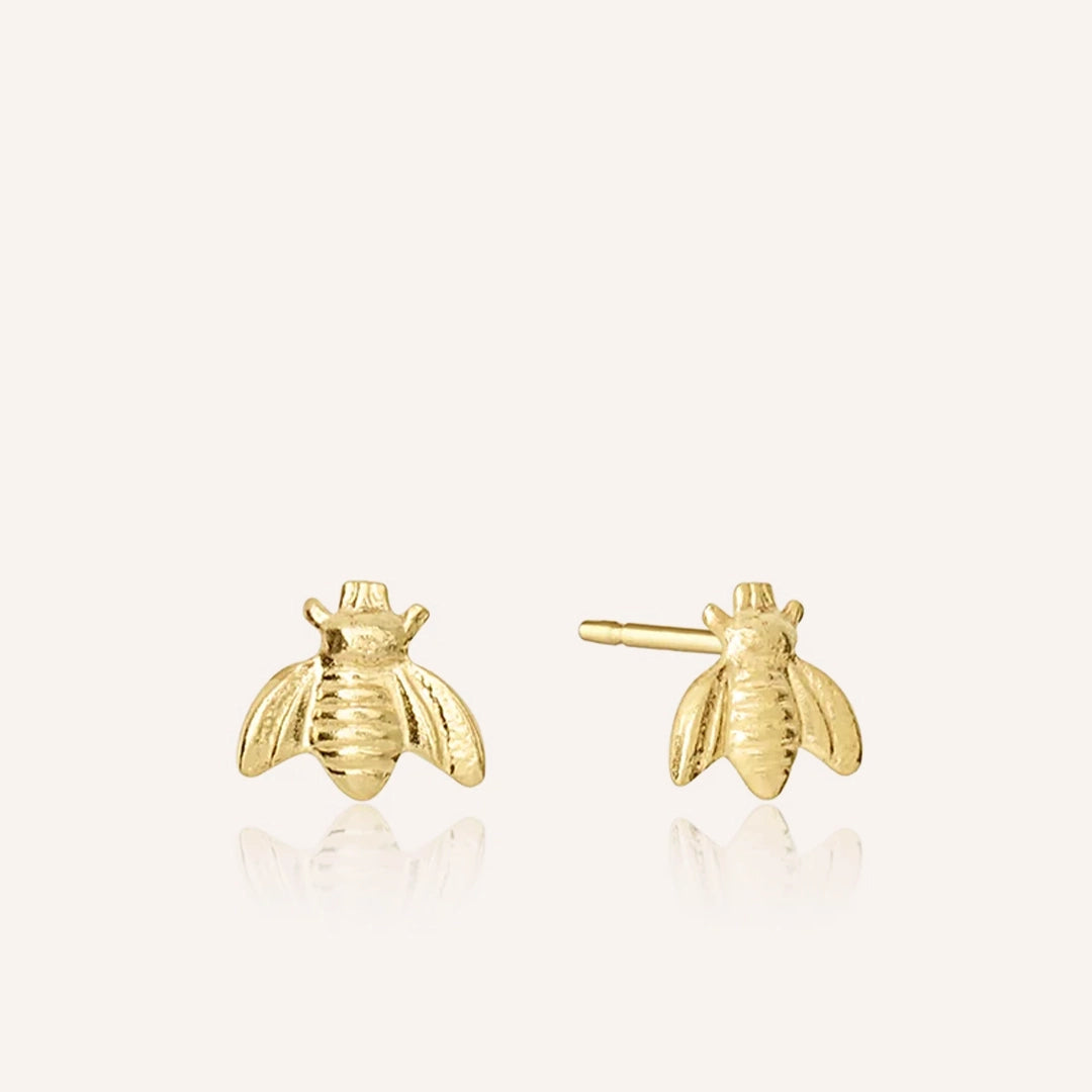Small gold bee charm stud earrings.