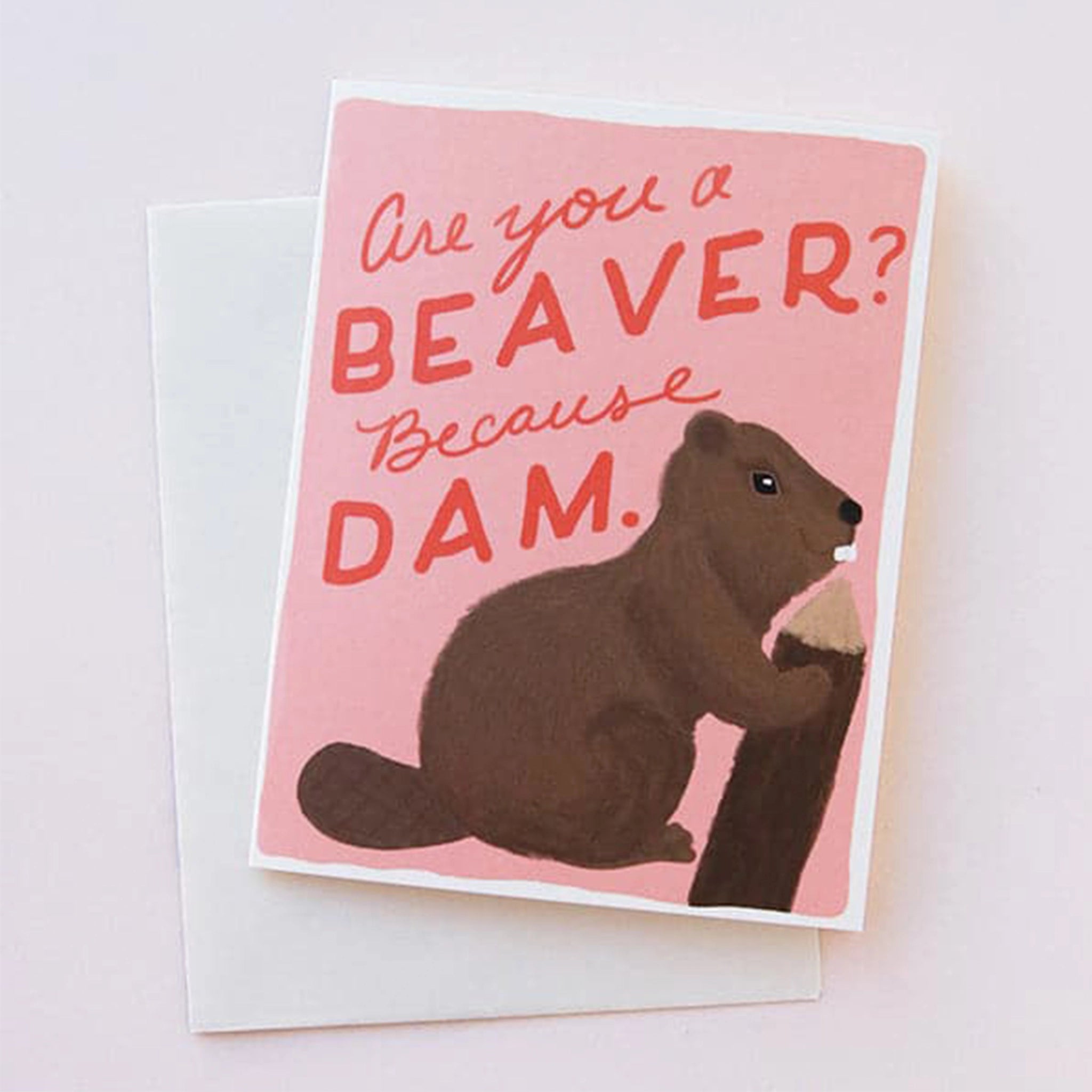 A pink greeting card with a graphic of a brown beaver on the front with red text that reads, &quot;Are you a beaver? Because dam.&quot;