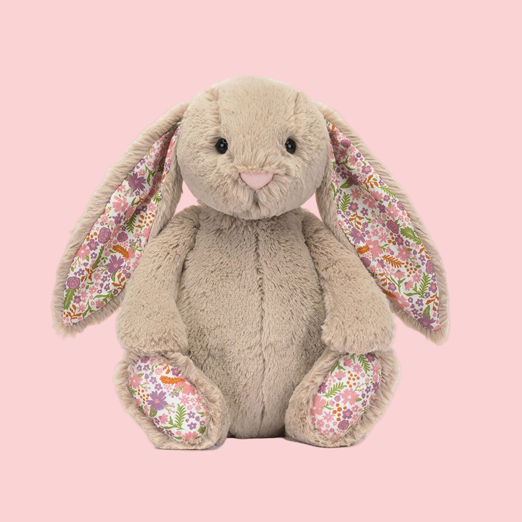 A beige bunny shaped stuffed animal toy with a floral pattern in the ears and on the feet. 