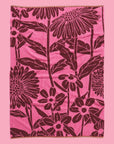 On a pink background is a pink and burgundy floral print bath towel. 