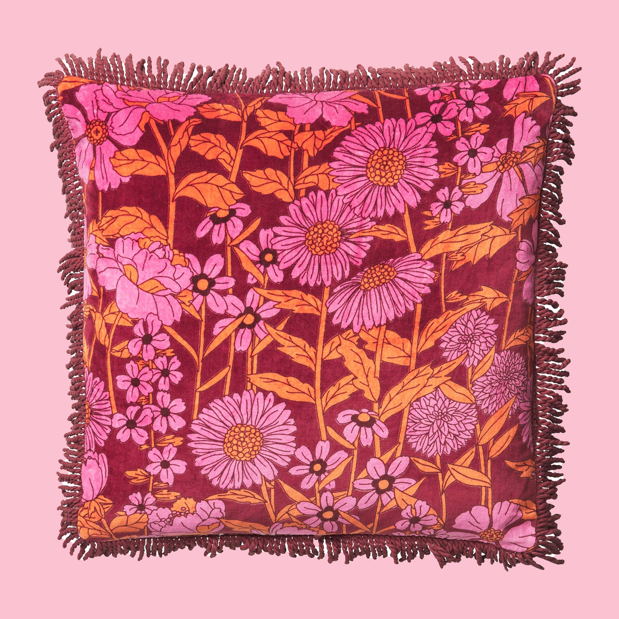 A pink and orange floral printed pillow with a fringe detail. 
