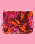 A pink, orange and rust colored floral print velvet pouch with a pink tassel zipper detail. 