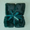 An emerald fur blanket with a satin ribbon and a mint tag that reads "bestie" tied onto it.