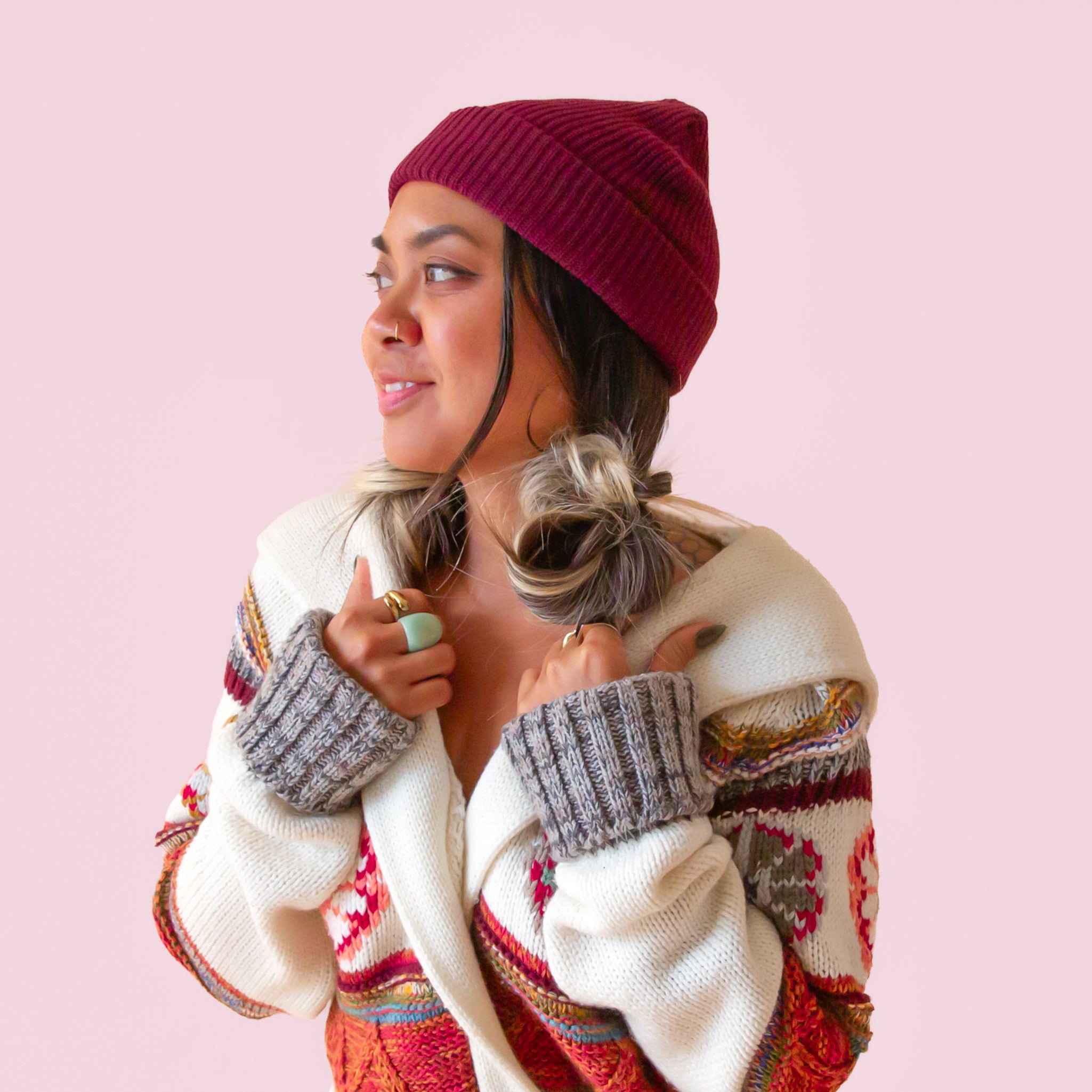 A girl in a cozy knit sweater wears a wine colored knit beanie.