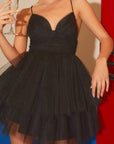A model wearing a black mini dress with a sweatshirt shaped neckline, thin straps and a two layered tulle skirt. 