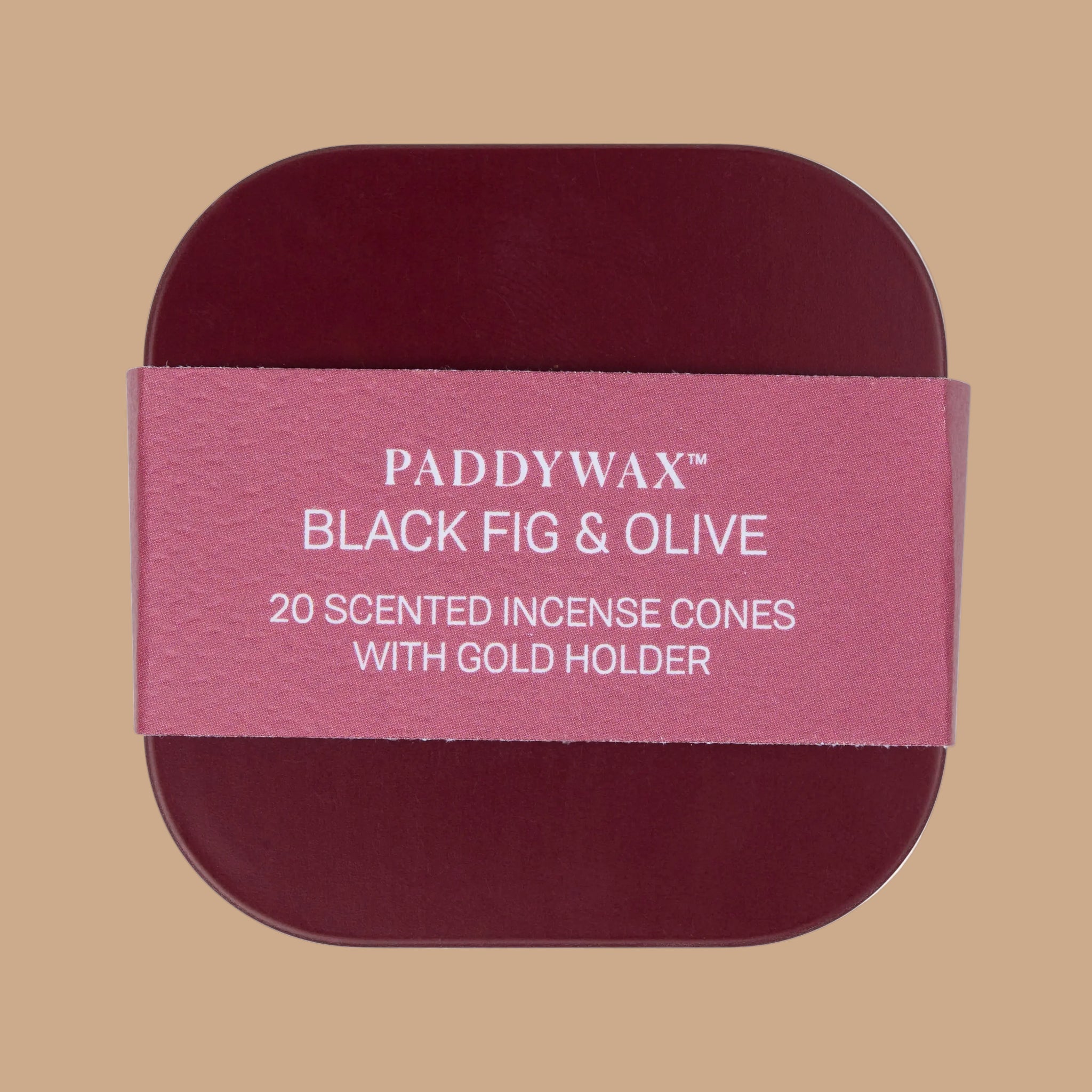 A burgundy tin filled with burgundy cone shaped incense and a gold tiny bowl for burning. 