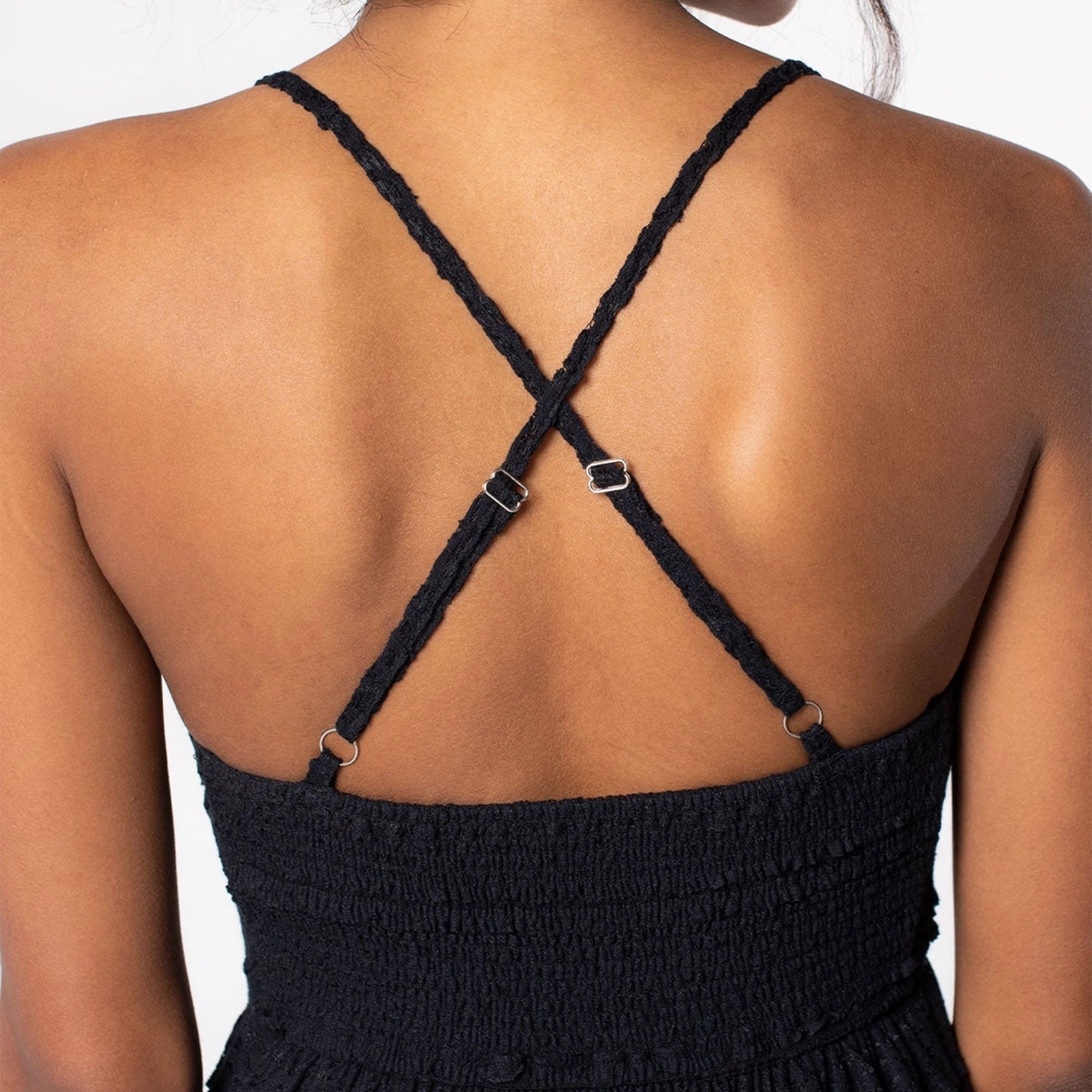A black lace flowy dress with a v-neck and spaghetti straps that cross in the back.