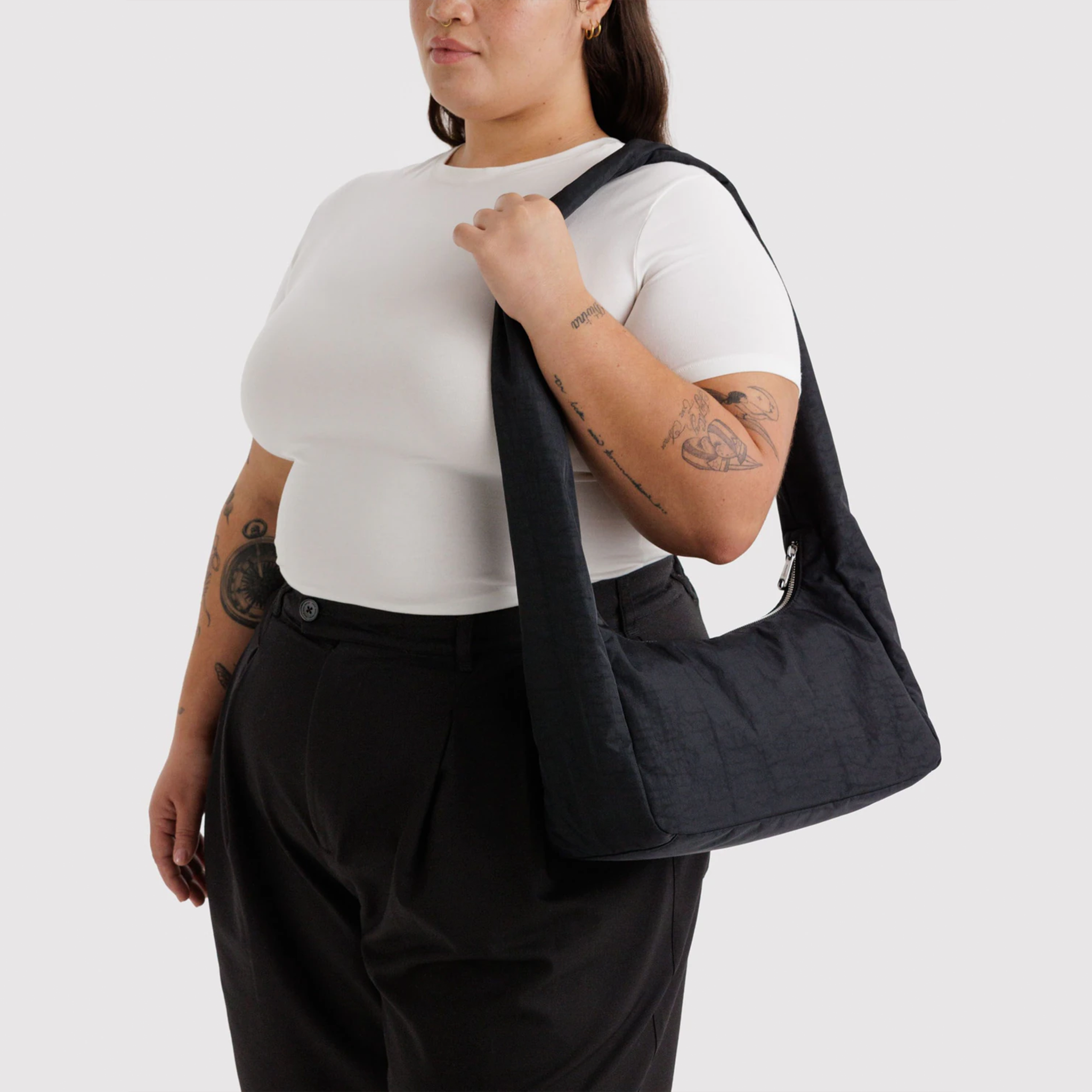 A black nylon shoulder bag with long shoulder straps on a model's shoulder.