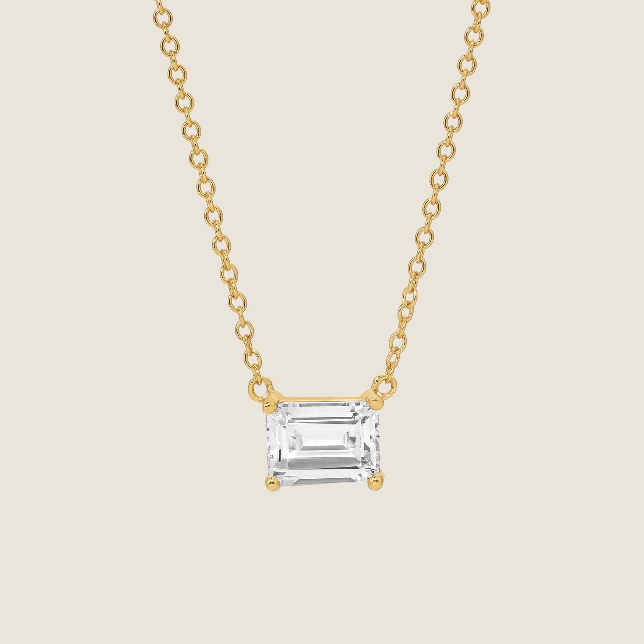 A gold chain necklace with a clear emerald cut cz stone in the center. 