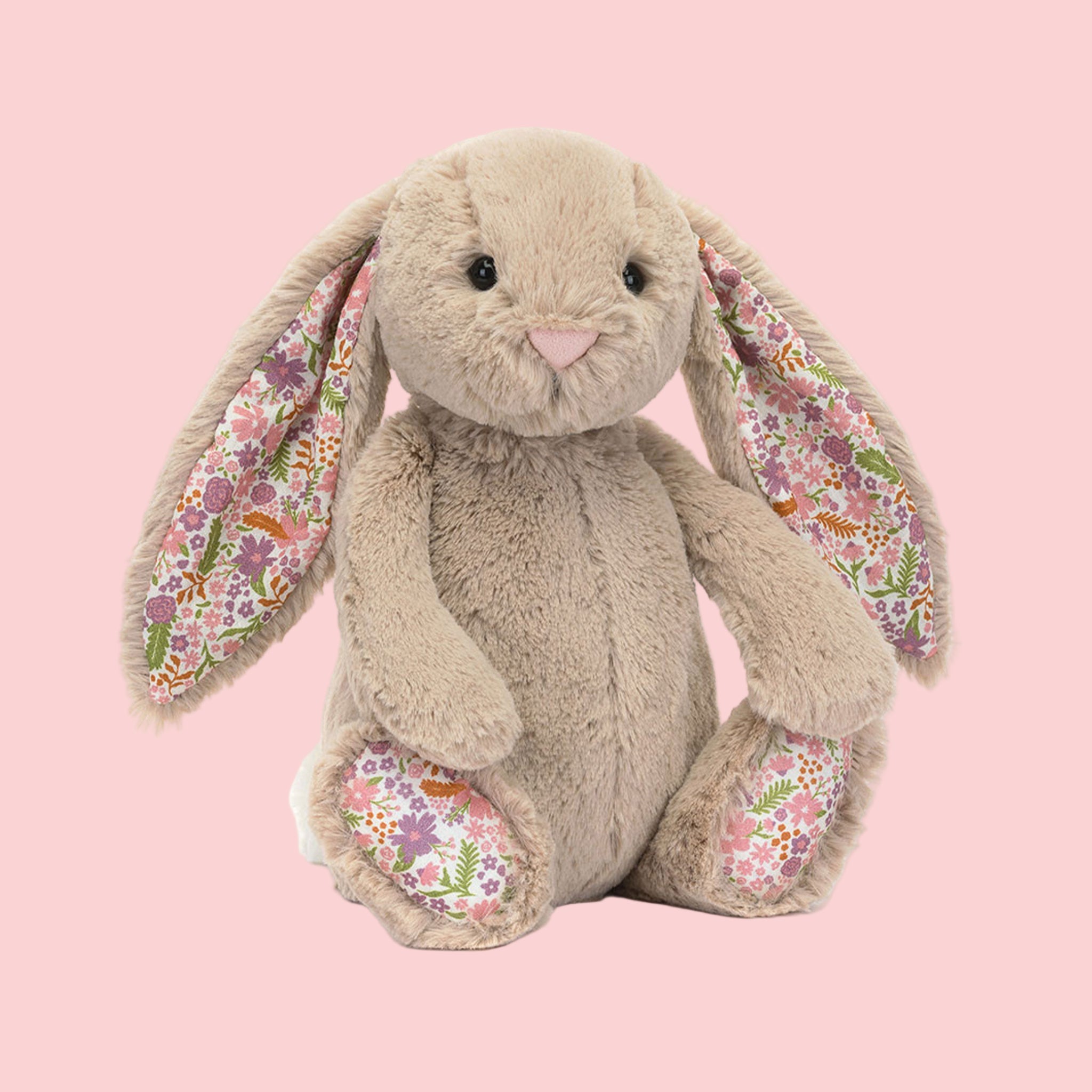 A beige bunny shaped stuffed animal toy with a floral pattern in the ears and on the feet.