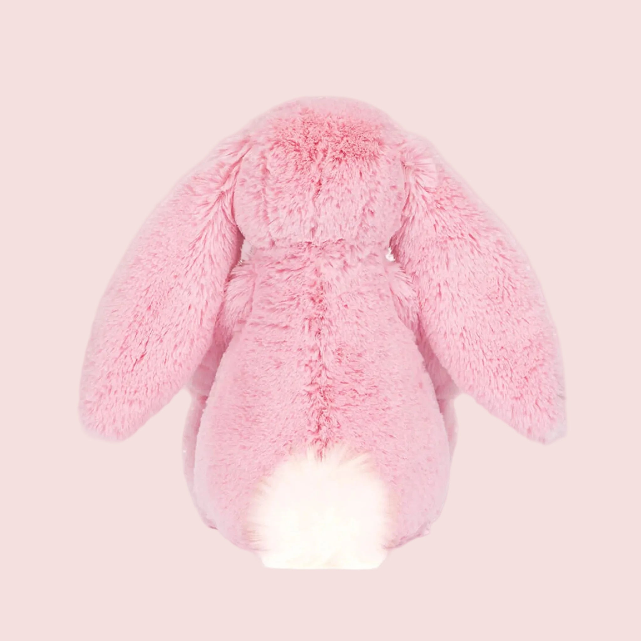 A pink bunny shaped stuffed animal. 