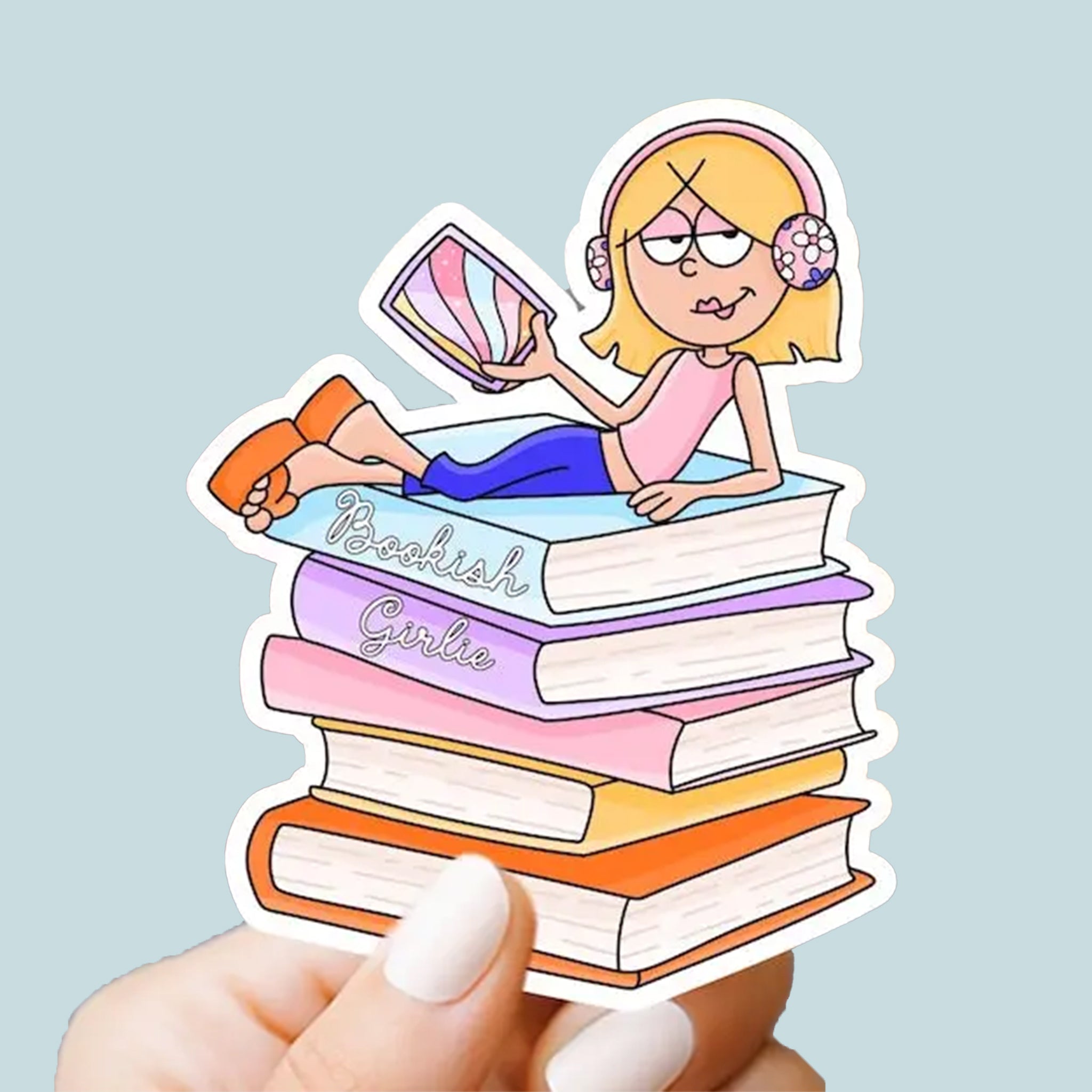 Cartoon sticker of a girl on books with 'Bookish Girlie' text, held against a light blue background.