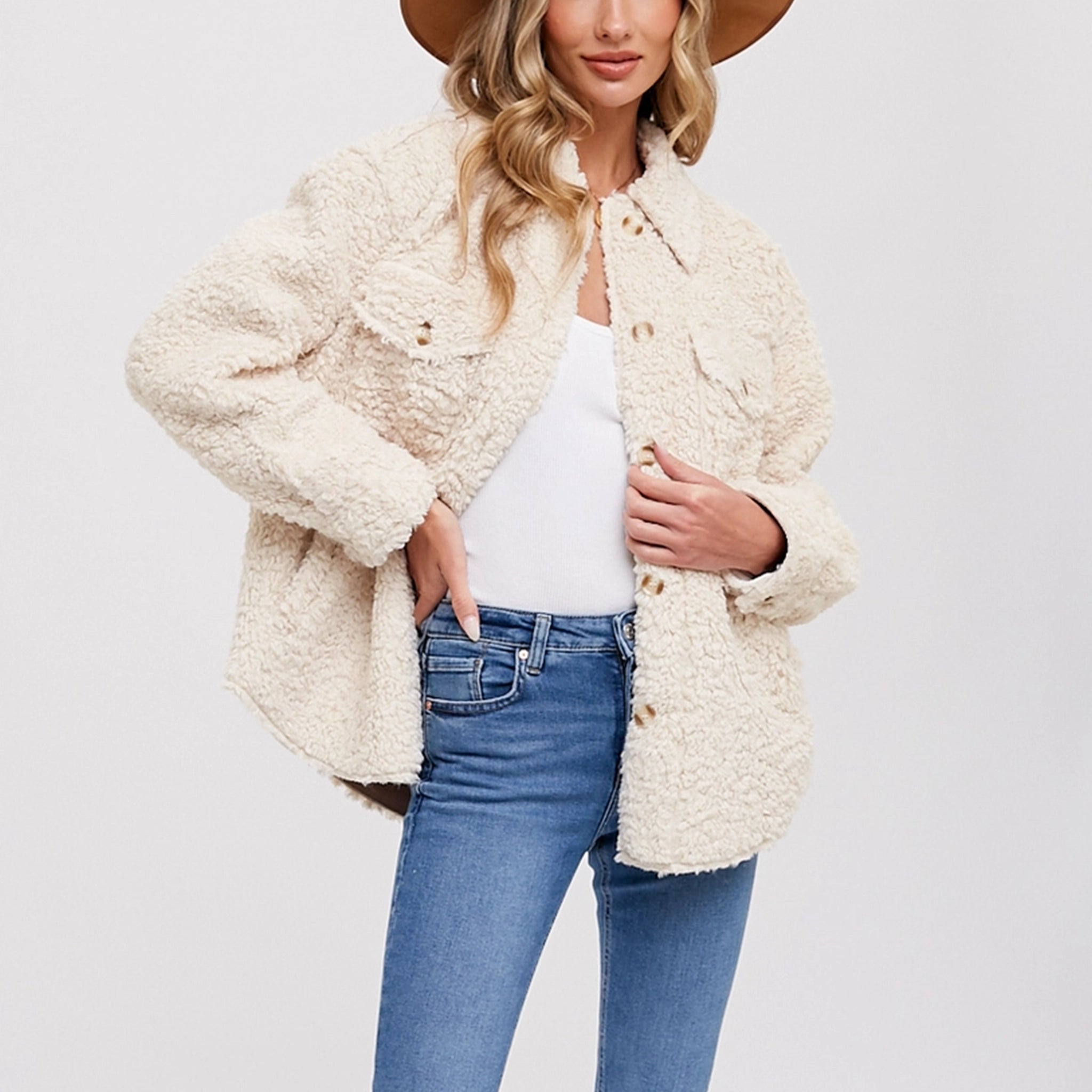On a white background is a model wearing a boucle shirt jacket with buttons and front pockets.
