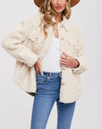 On a white background is a model wearing a boucle shirt jacket with buttons and front pockets.