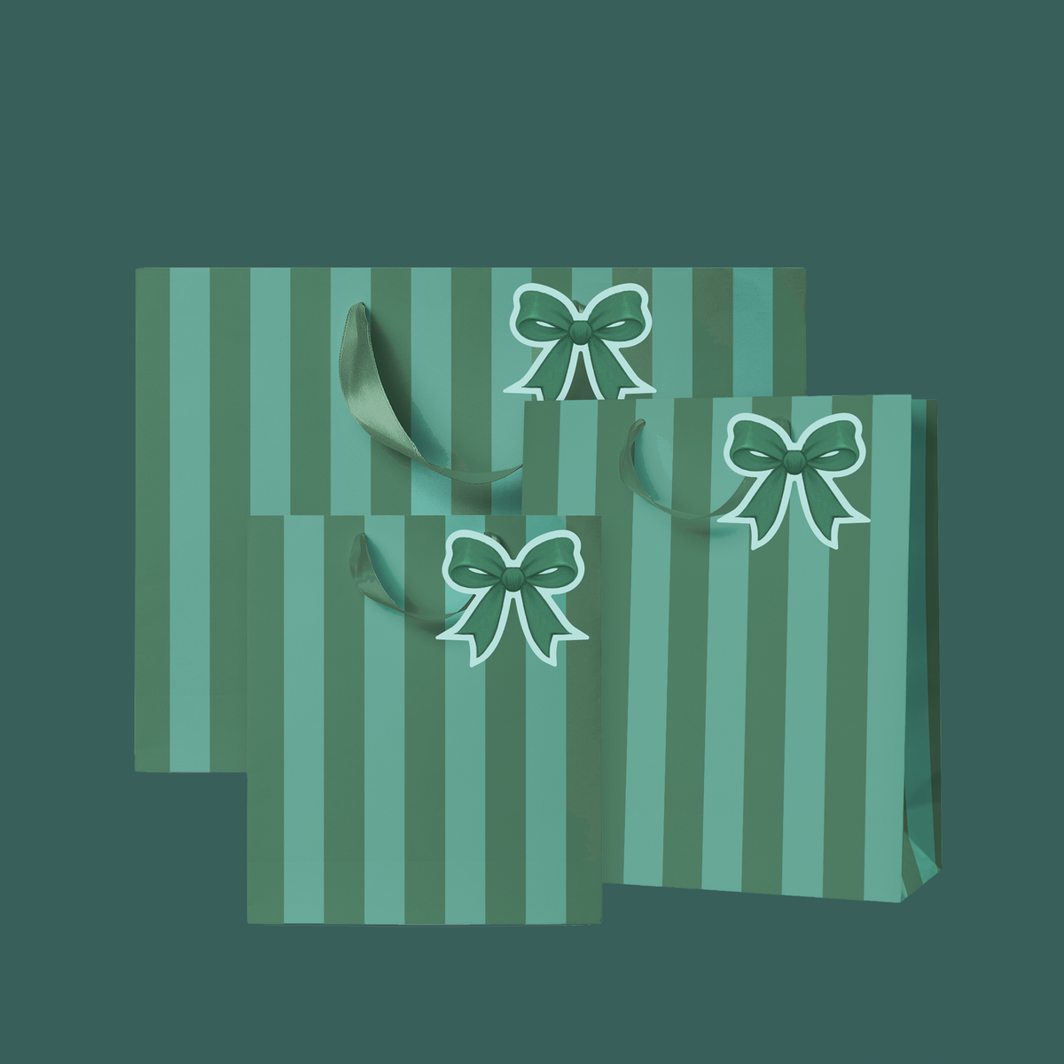 Three gift bags with vertical stripes in shades of green and teal, featuring printed green bows with white outlines and matching green handles, set against a solid pale mint green background.