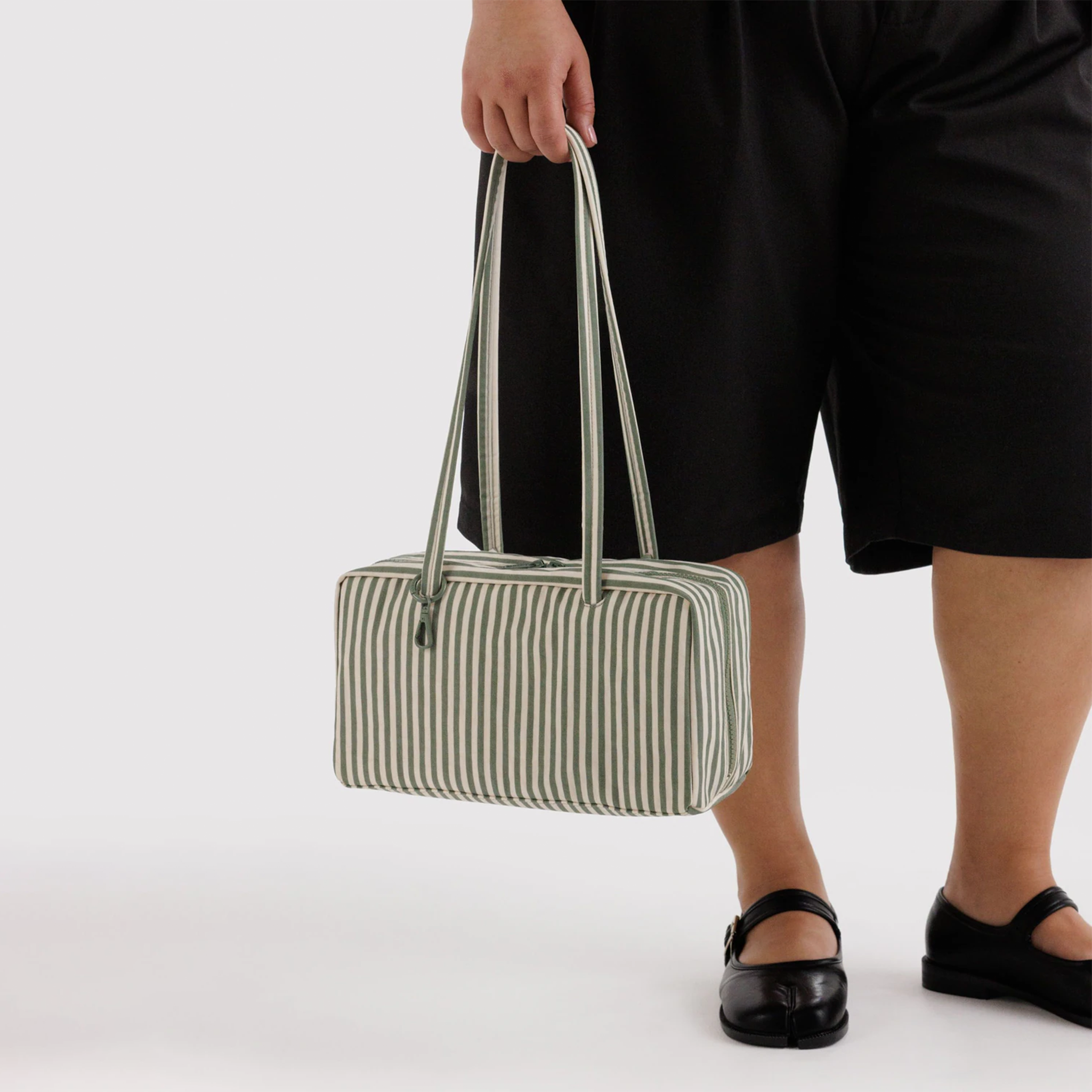 sage striped nylon bag being held by a model.