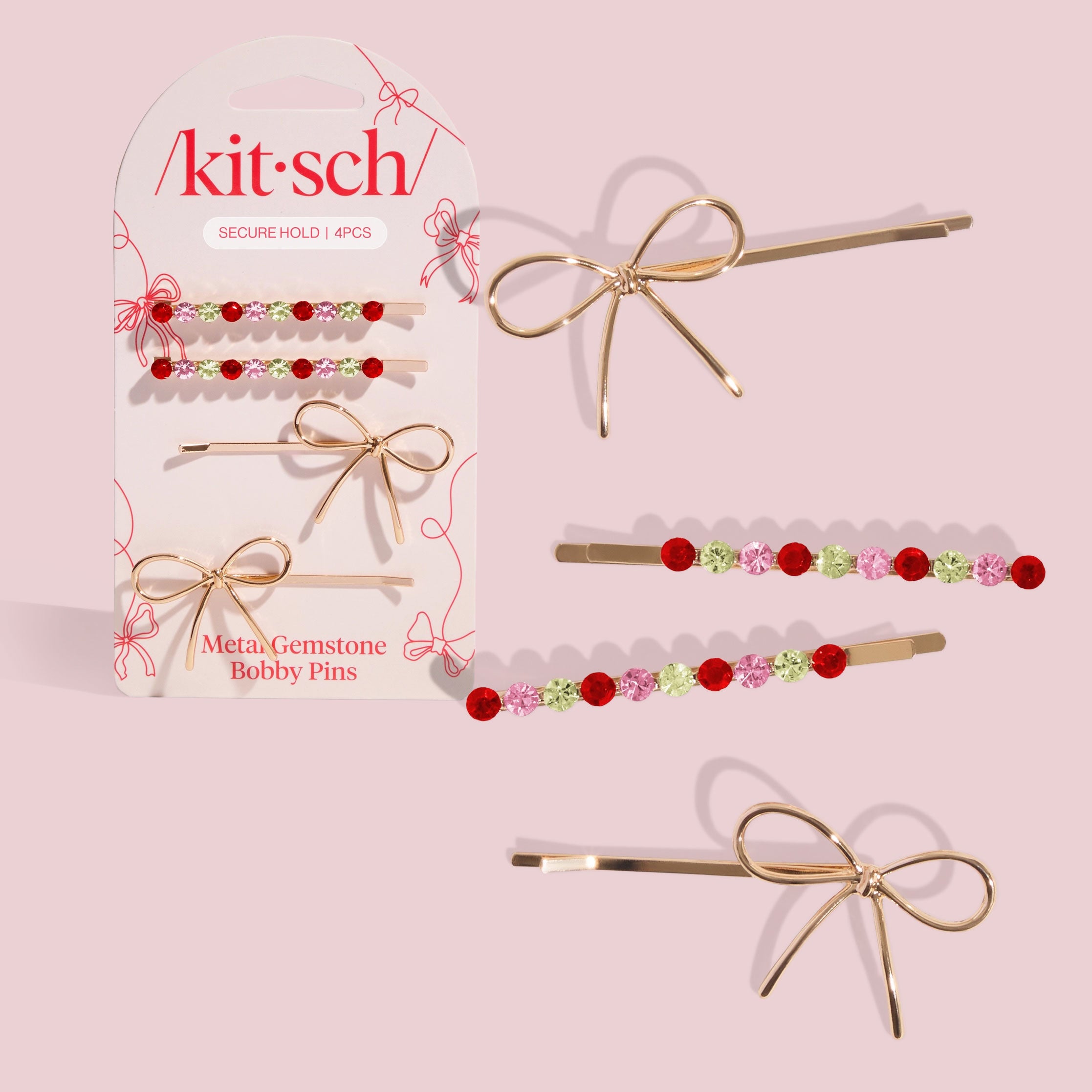 Kitsch ‘Metal Gemstone Bobby Pins’ display card on a pale pink background, shown with four bobby pins: two gold bow-shaped pins and two pins lined with red, pink, and green gemstones, with extra pins laid out beside the packaging.