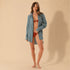 Woman wearing a blue shirt over a red bikini on a beige background