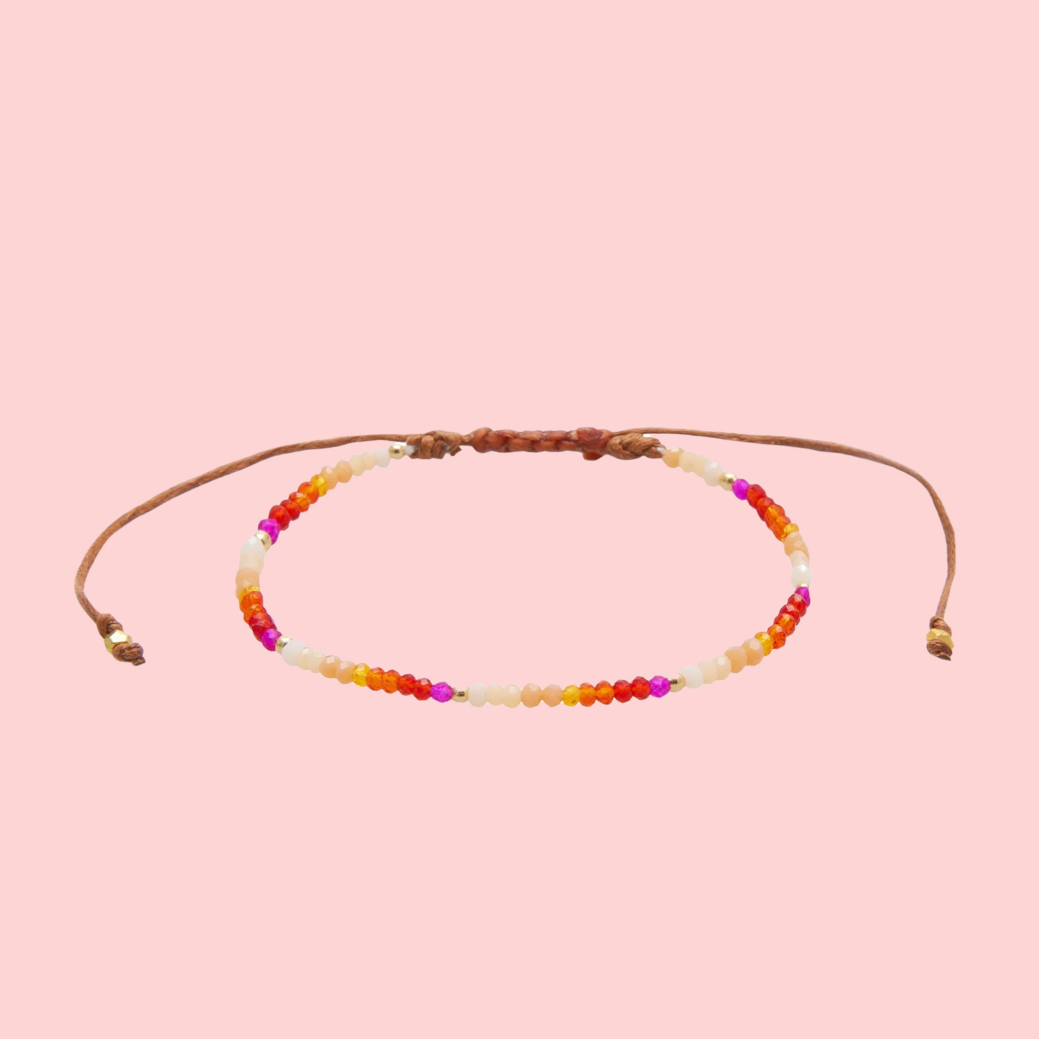 A multi colored beaded bracelet on a pink background with an adjustable tie. 