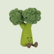 A broccoli shaped stuffed toy with a smiling face. 