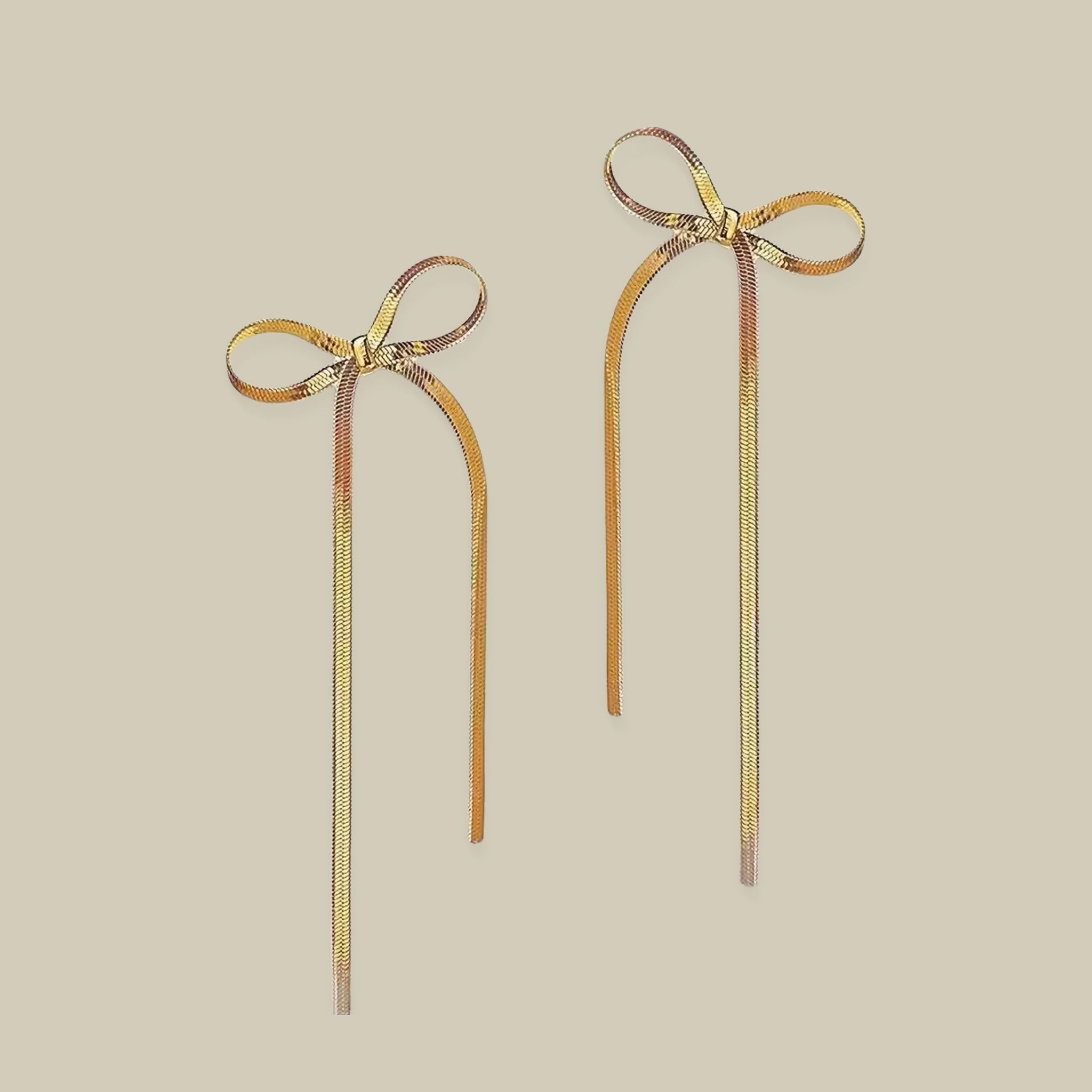 A pair of gold bow shaped earrings with dangles. 