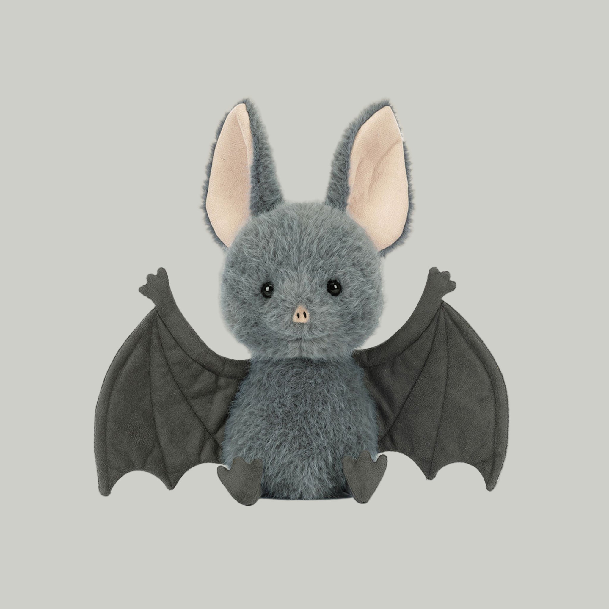 A grey bat shaped stuffed animal toy. 