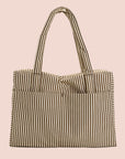On a light pink background is a brown and white striped travel bag tote.