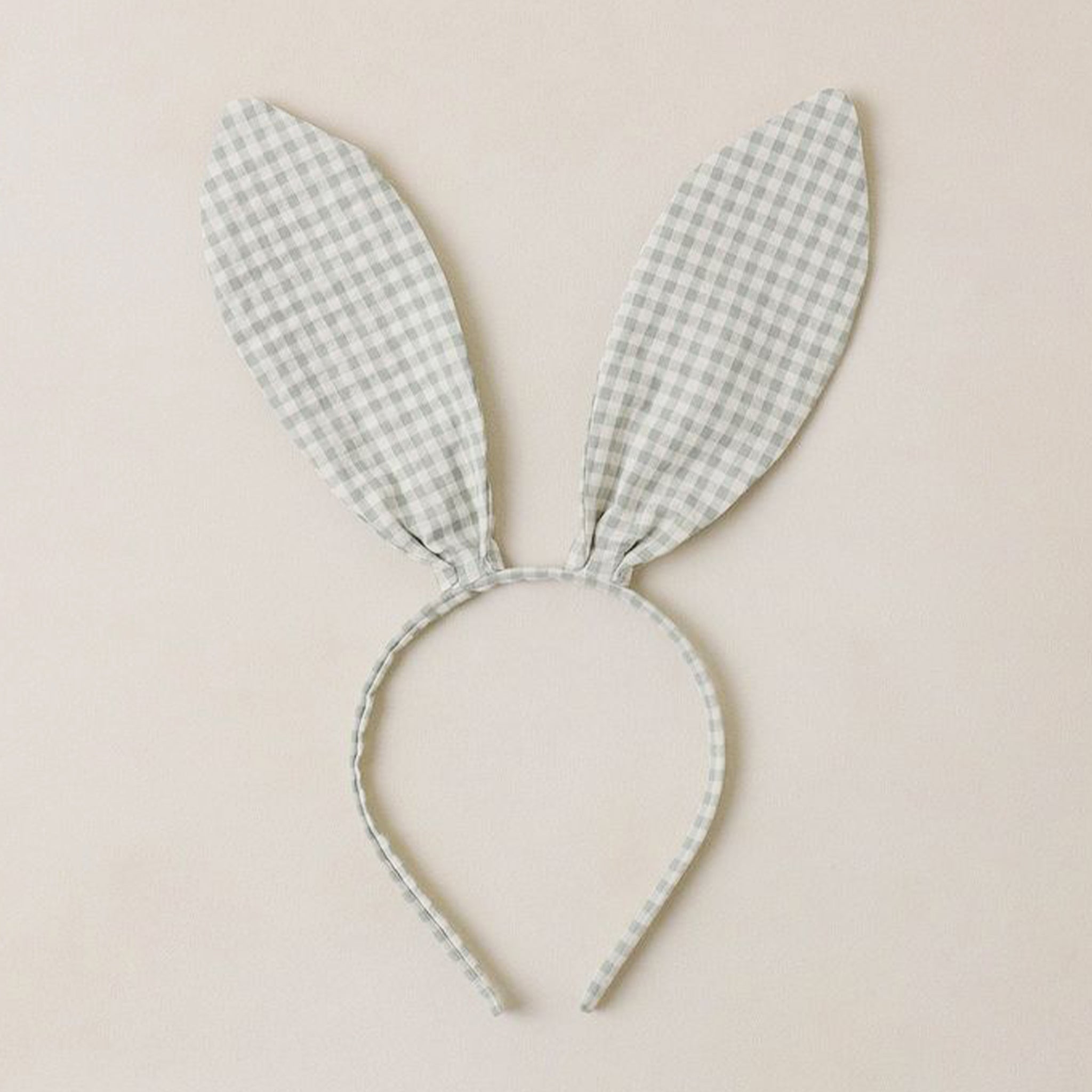 A bunny ear shaped headband with a light sage and cream checker print. 