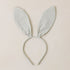 A bunny ear shaped headband with a light sage and cream checker print. 