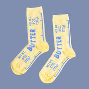 A pair of light yellow socks with blue text that looks like a butter label. 