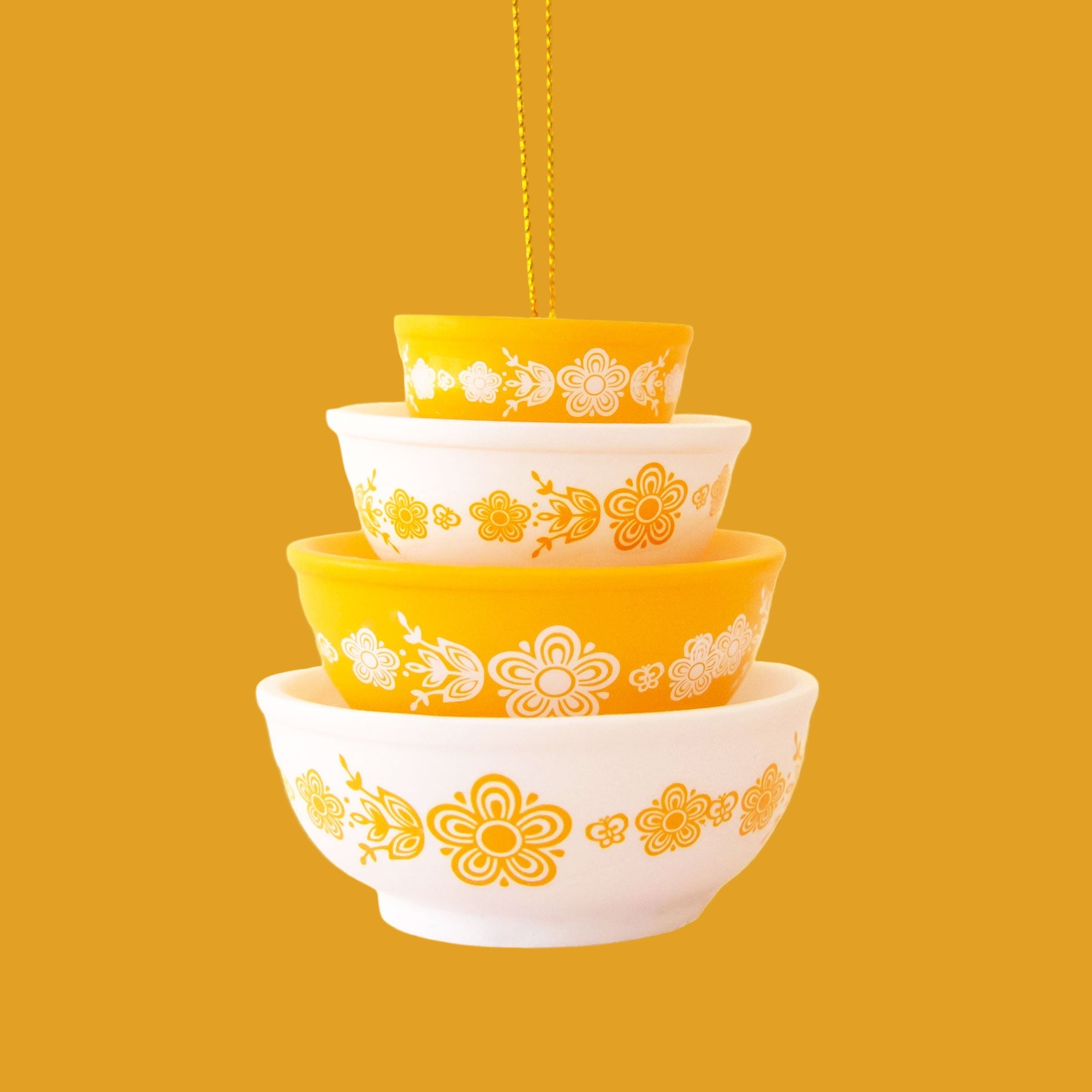 A yellow and cream colored ornament in the shape of stacked bowls. 