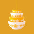 A yellow and cream colored ornament in the shape of stacked bowls. 
