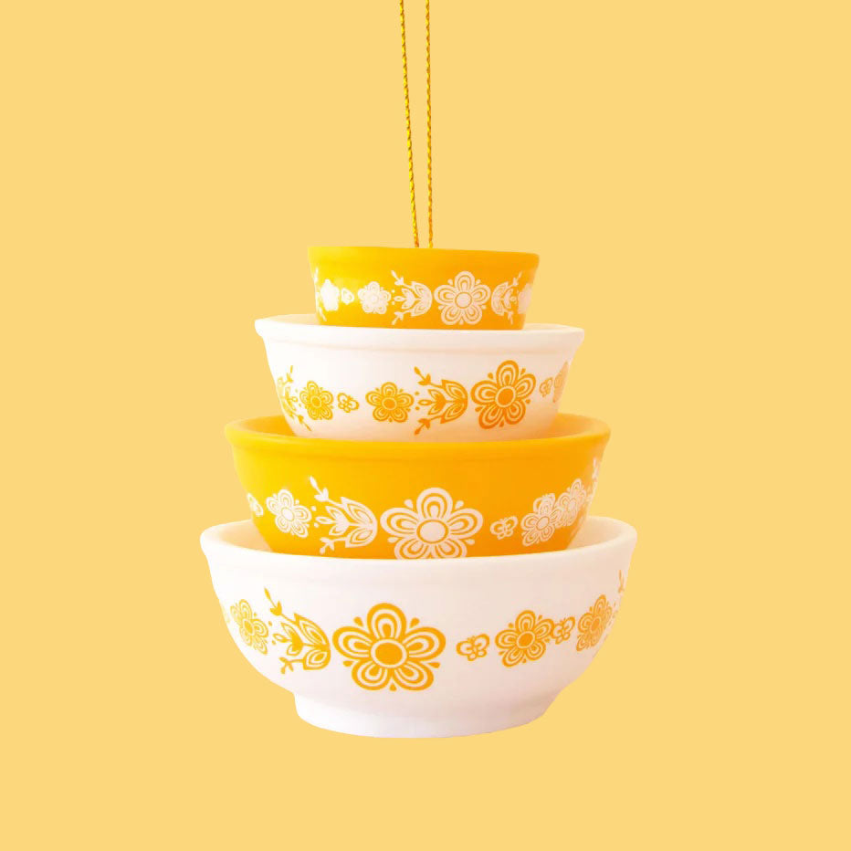 A yellow and cream colored ornament in the shape of stacked bowls. 
