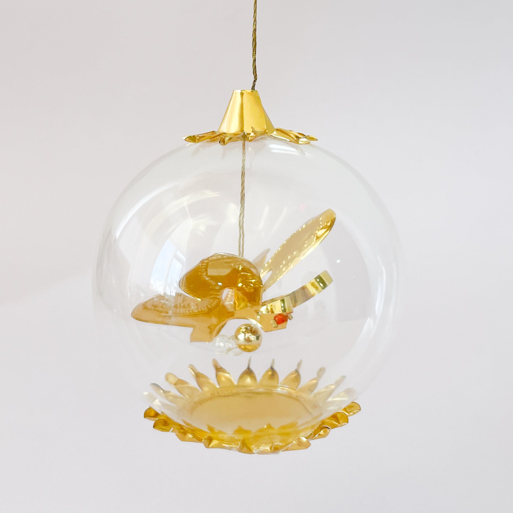 A clear round glass ornament hangs on a white background, containing a metallic gold butterfly figure and a gold cap on top.