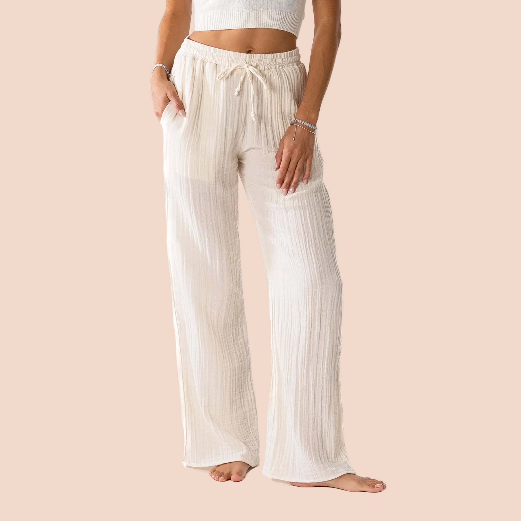 Person wearing a pair of cream colored pants with a drawstring. 