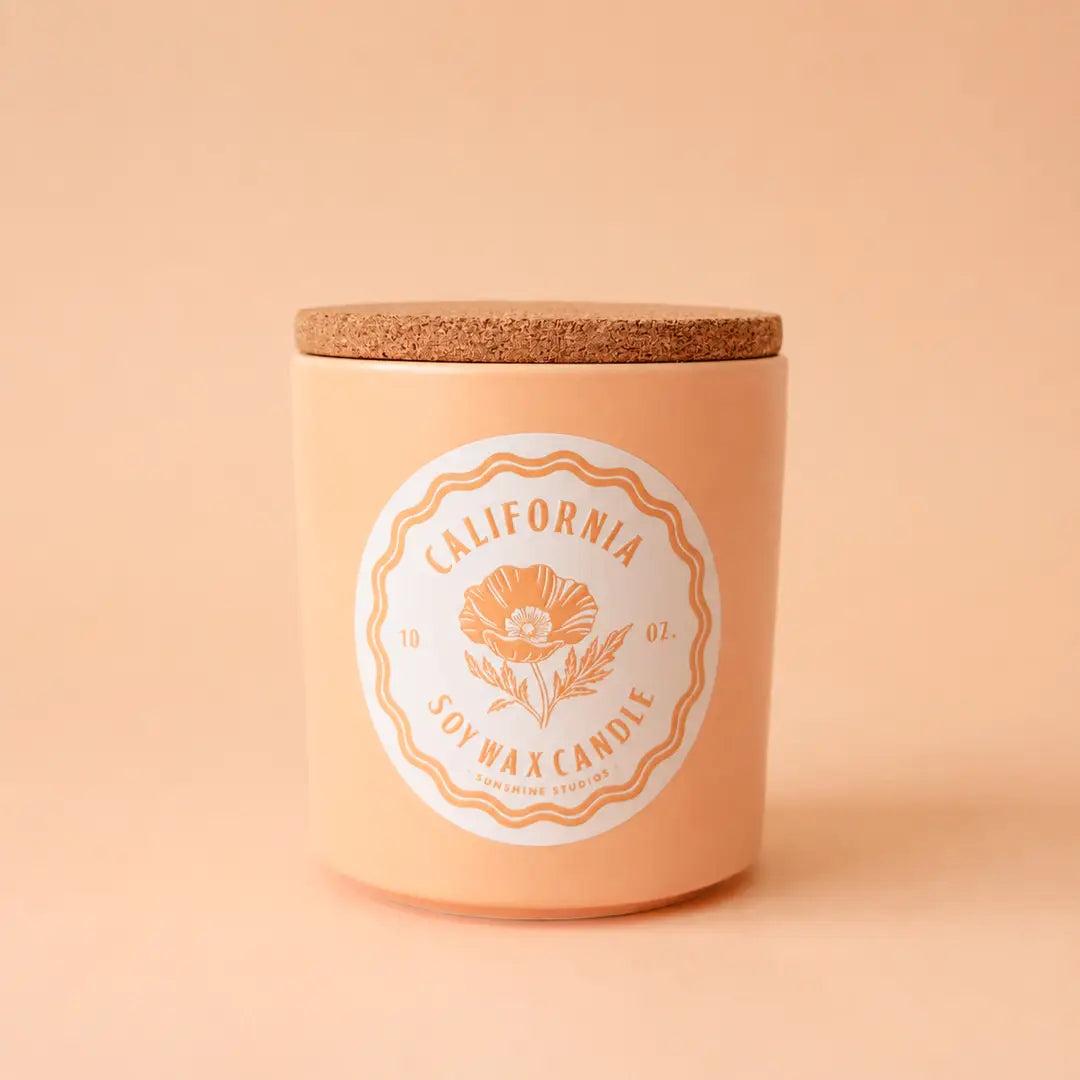 A peach colored ceramic candle with a cork lid.  The label says "California Soy wax candle" and a poppy graphic.