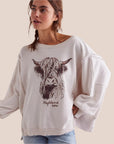 A white flowy top with a graphic of a brown highland cow and text underneath that reads, 'Highland cow'.