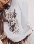 A white flowy top with a graphic of a brown highland cow and text underneath that reads, 'Highland cow'.