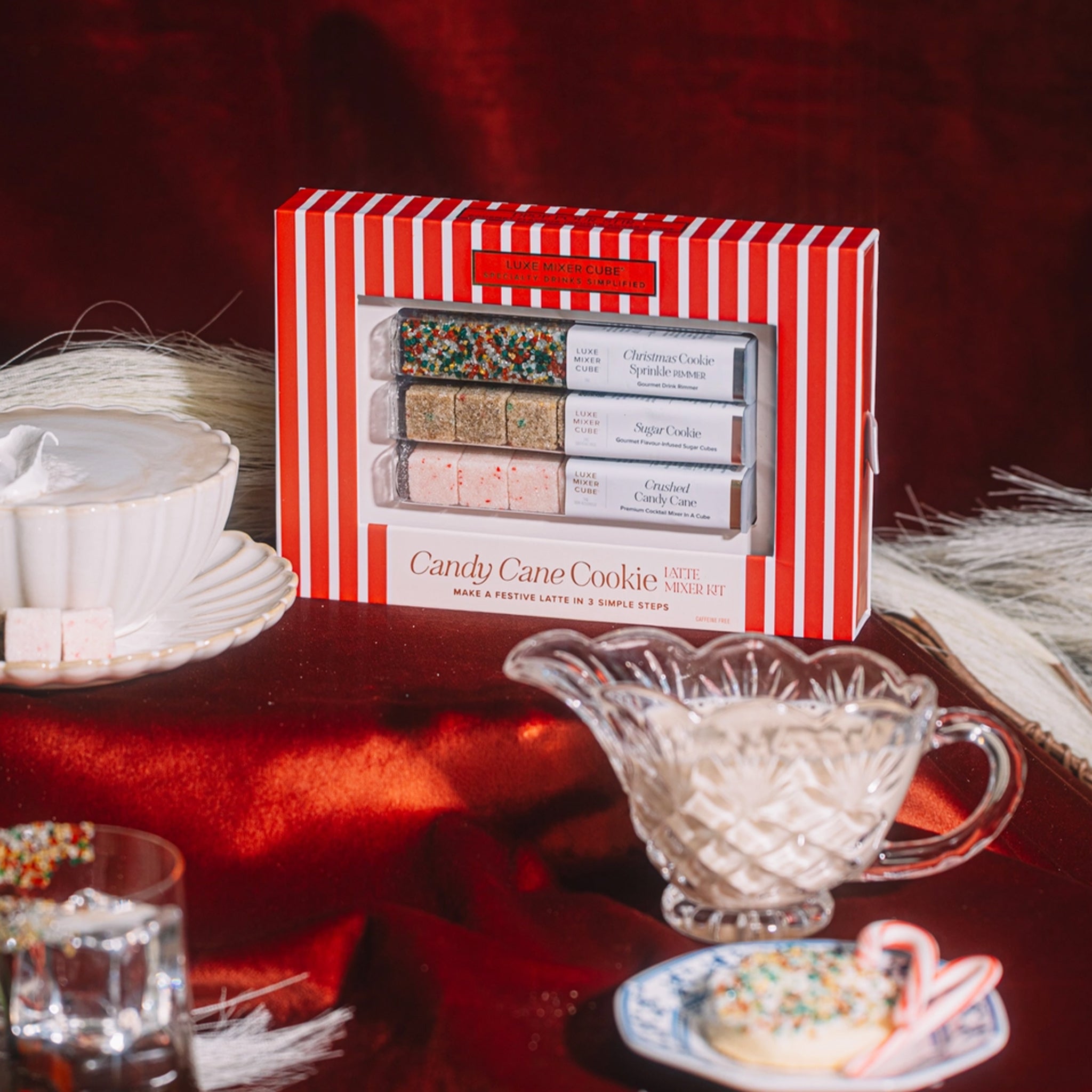 Red and white striped box of candy cane cookies on a table with decorative items.