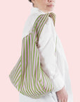 A light pink and green striped nylon reusable tote bag.