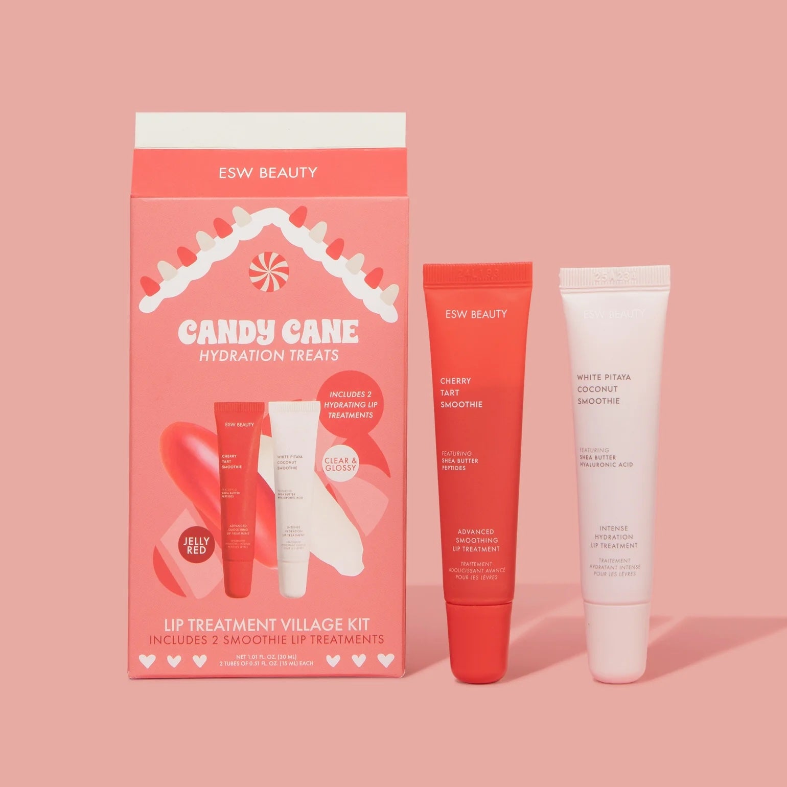 ESW Beauty ‘Candy Cane Hydration Treats’ lip treatment kit box beside two lip treatment tubes—one red ‘Cherry Tart Smoothie’ and one white ‘White Pitaya Coconut Smoothie’—on a pink background.