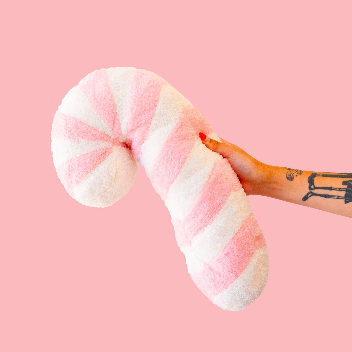 A light pink and white striped candy cane shaped pillow. 