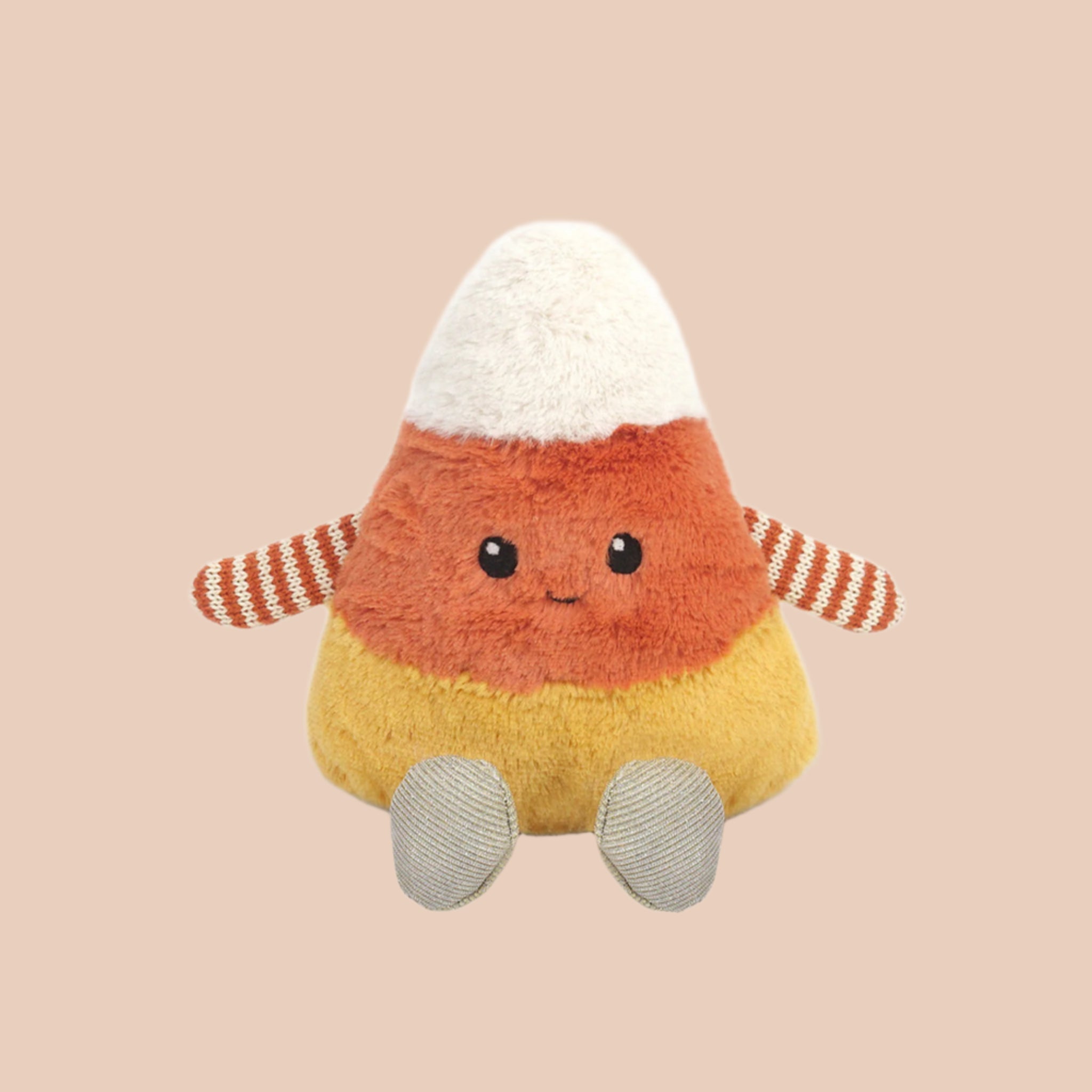 A white, orange and yellow candy corn shaped stuffed toy with a smiling face and orange and white arms and legs. 