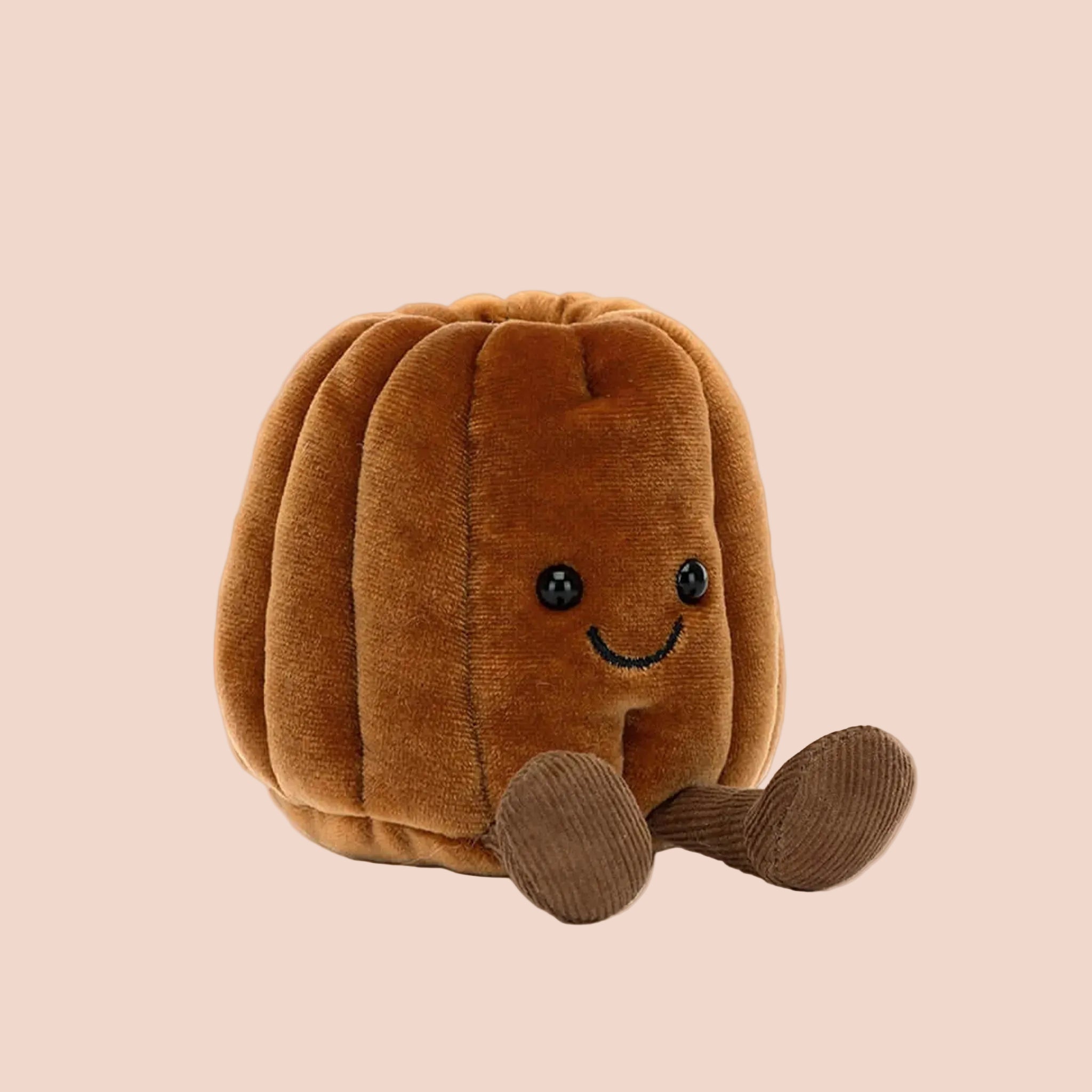 A canele shaped stuffed toy with a smiling face and brown corduroy legs and feet. 