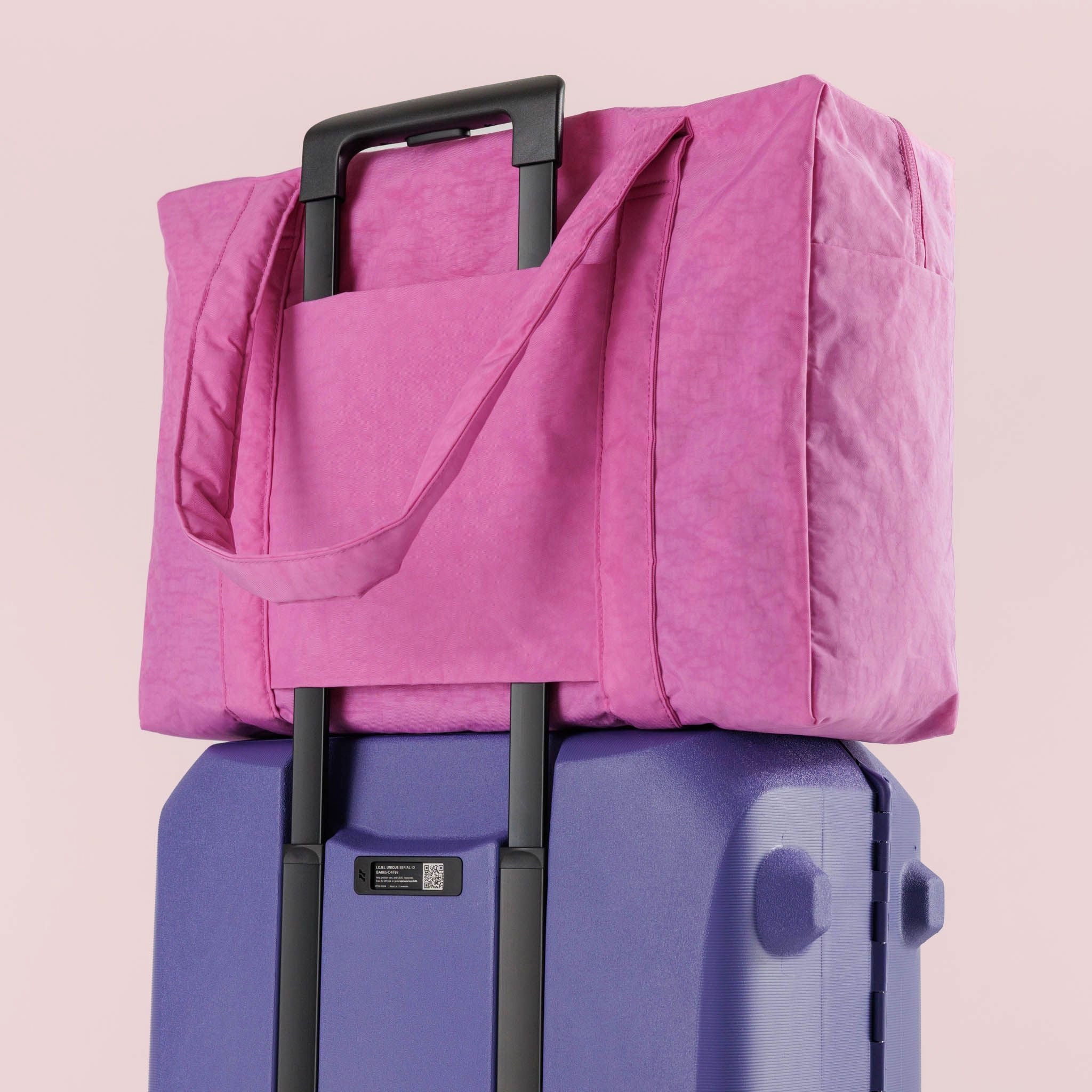 The extra pink cloud bag on a suitcase handle showing the slip feature that keeps the bag in place.