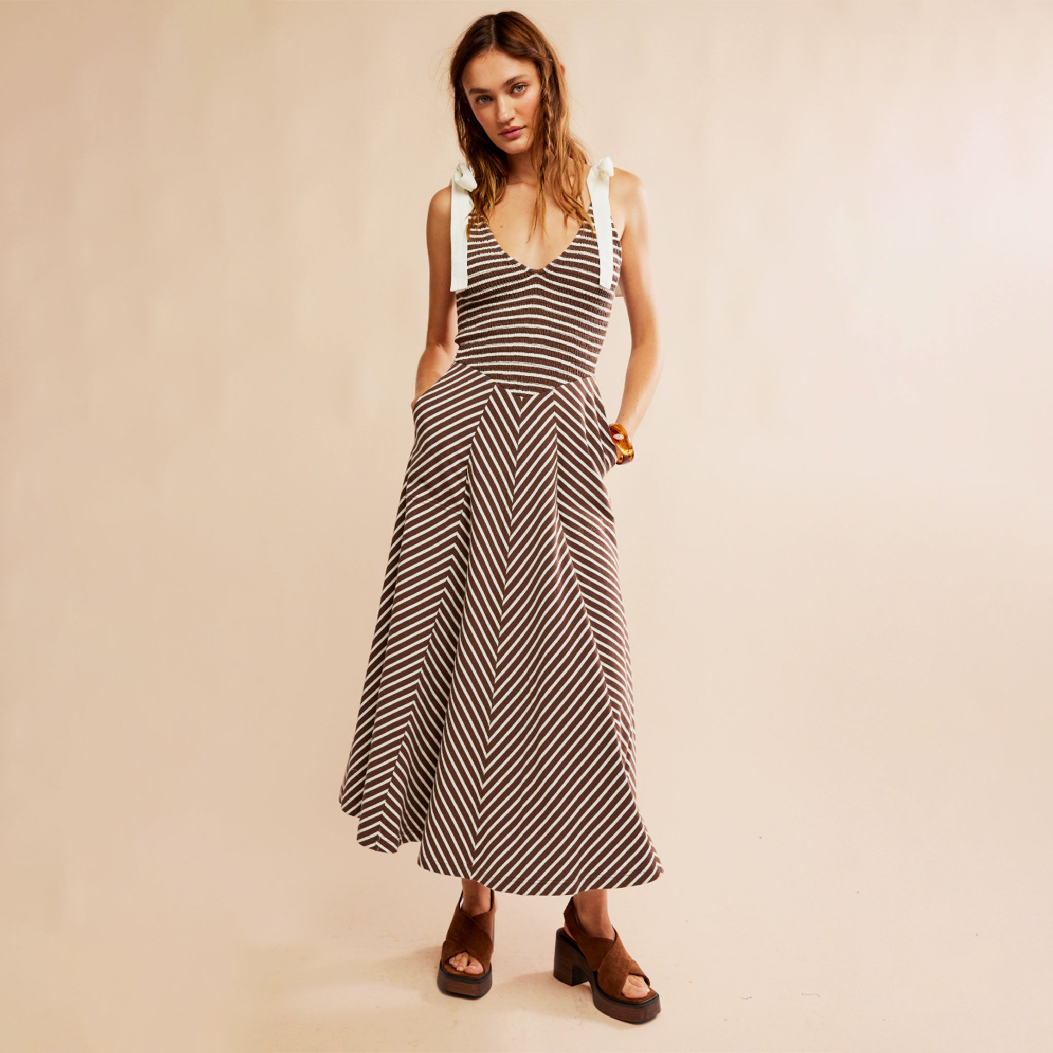 A striped neutral dress with white shoulder strap tie details.