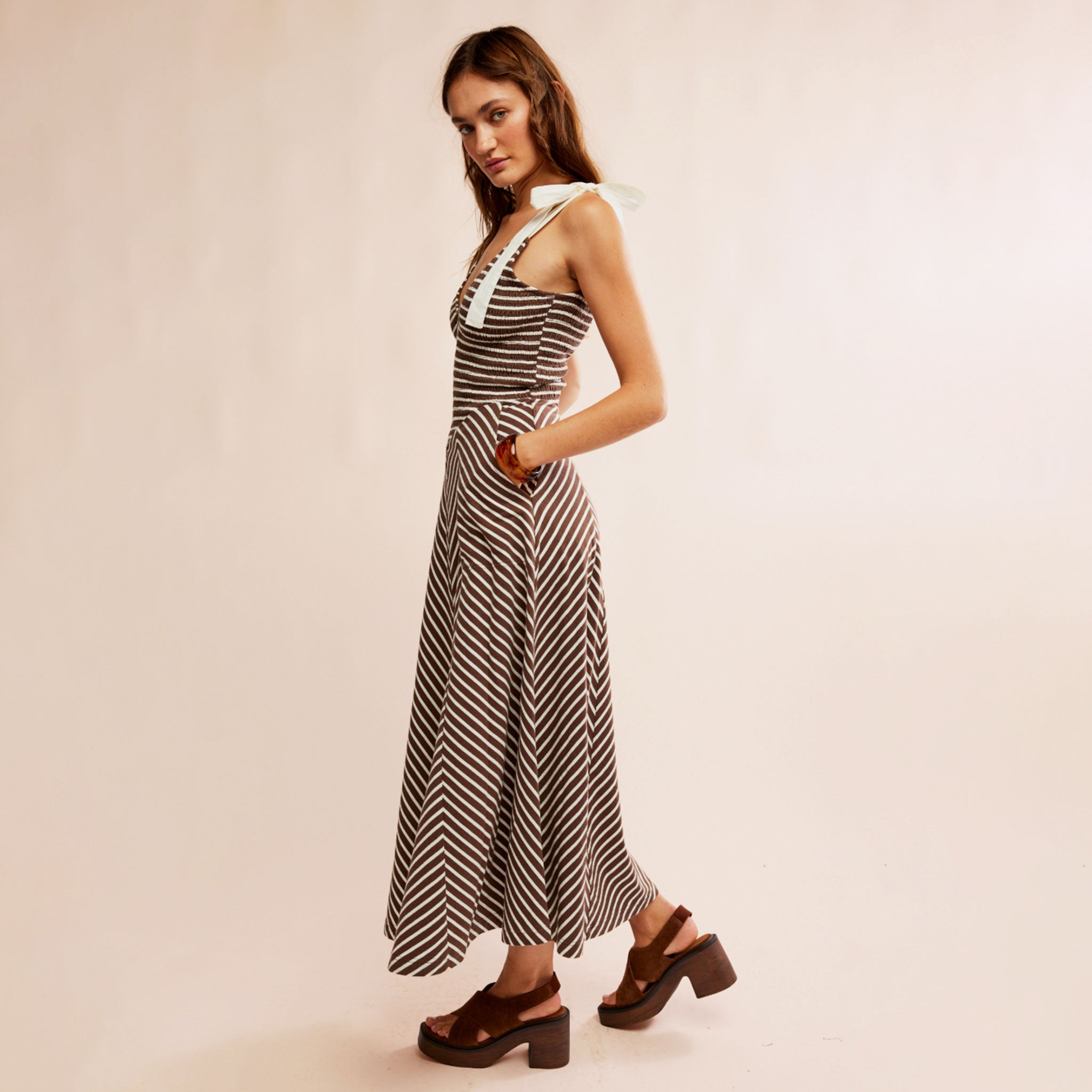 A striped neutral dress with white shoulder strap tie details.