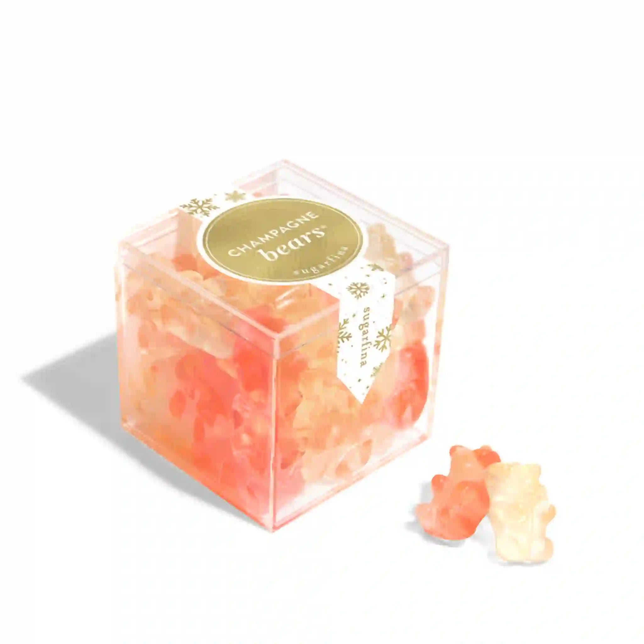 On a white background is a clear acrylic box filed with pink champagne bear gummies with a gold and white label on the front that reads, 'Champagne Bears".