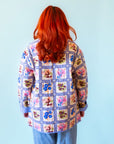 A multi colored quilted jacket with a floral print on one side and a blue solid color on the other. 